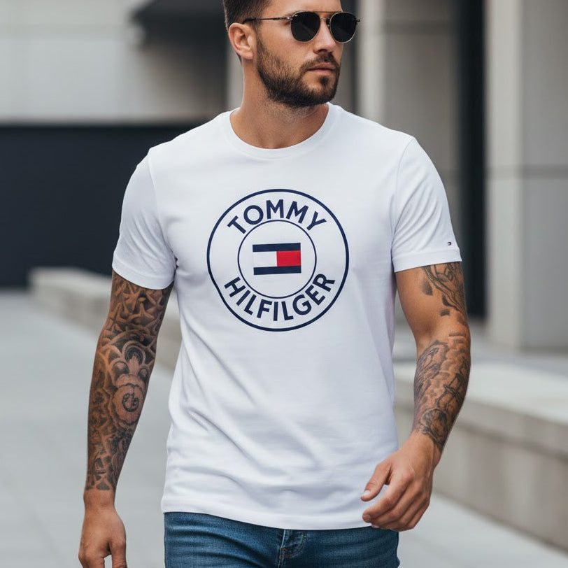 Мъж с бяла тениска Tommy Hilfiger с голямо кръгло лого и дънки